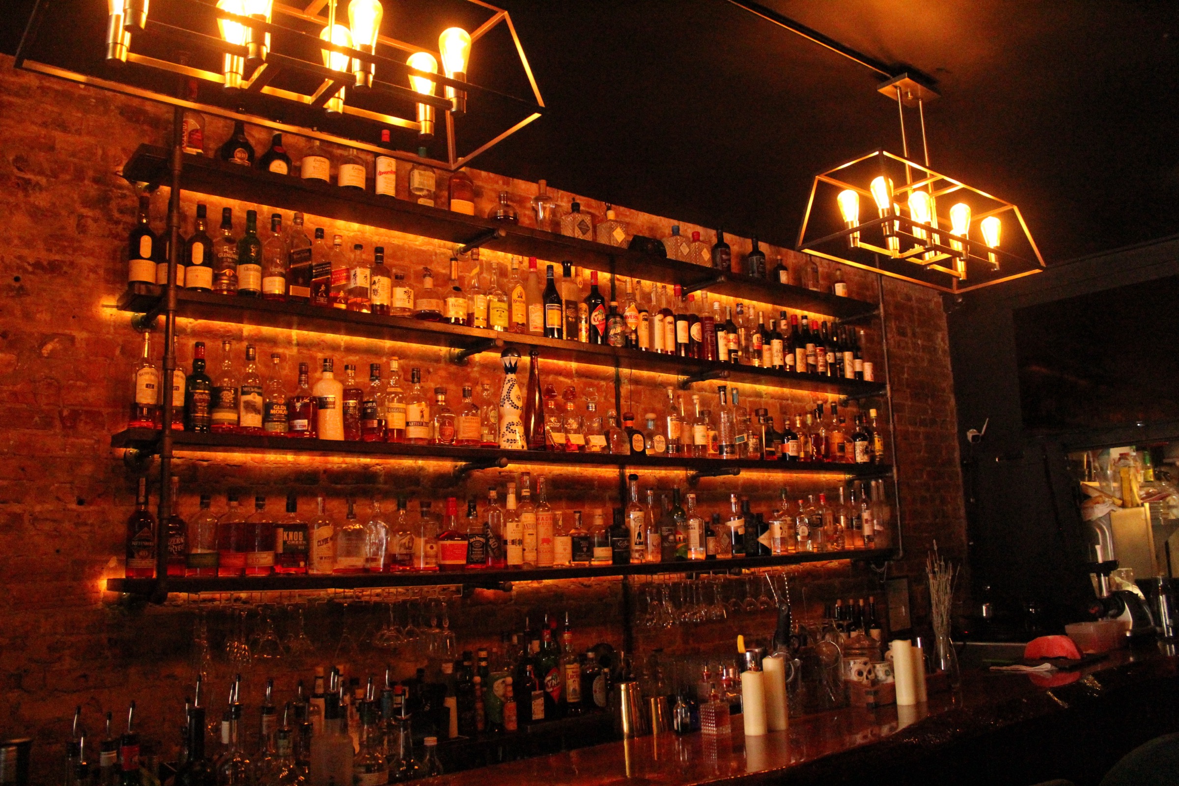 The back bar at Aura, lit warm against exposed brick
